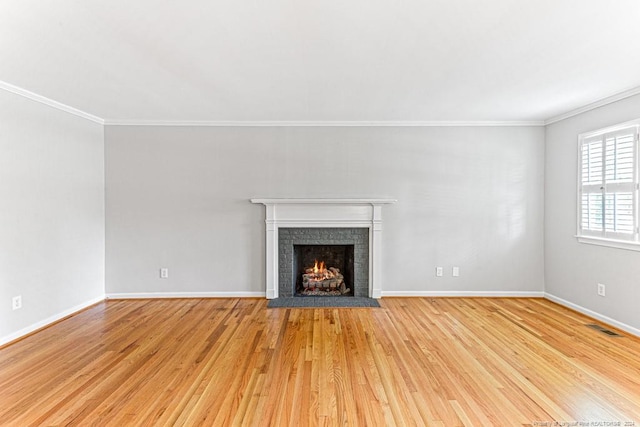 unfurnished living room with a fireplace, crown molding, and light hardwood / wood-style floors