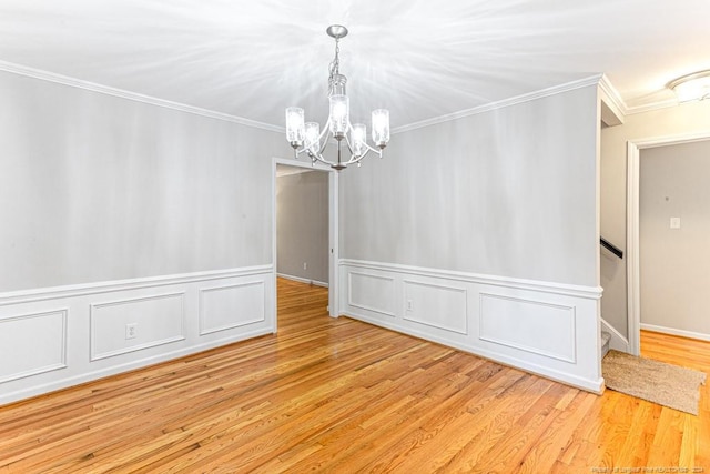 unfurnished room with crown molding, light hardwood / wood-style floors, and a chandelier