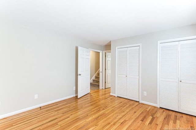 unfurnished bedroom with light hardwood / wood-style flooring and two closets