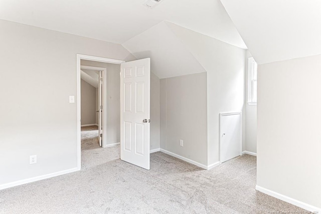 additional living space with light colored carpet and vaulted ceiling