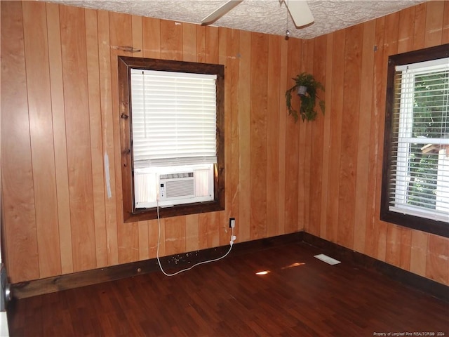 unfurnished room with a textured ceiling, plenty of natural light, and dark hardwood / wood-style flooring