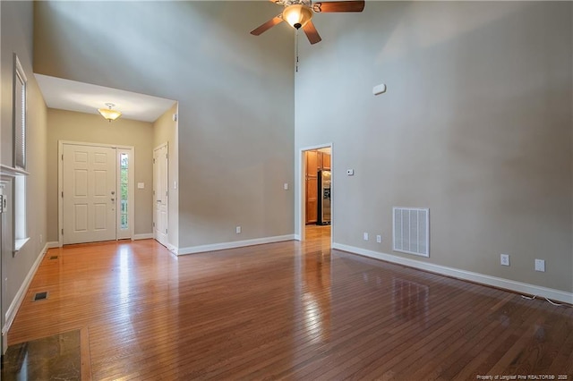 foyer entrance with a high ceiling, ceiling fan, and light wood-type flooring