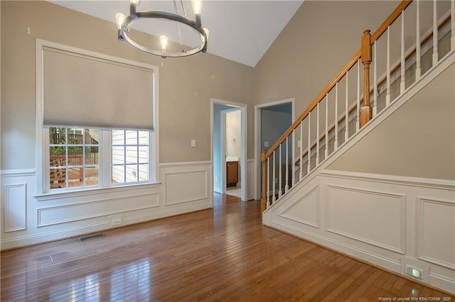 entryway featuring hardwood / wood-style flooring, vaulted ceiling, and a chandelier