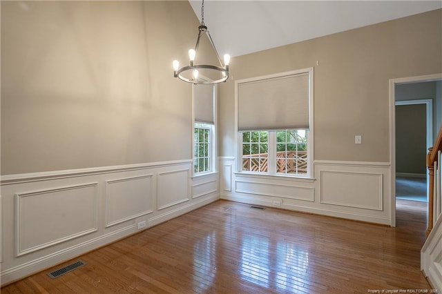 unfurnished dining area with an inviting chandelier and hardwood / wood-style floors