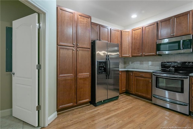 kitchen featuring tasteful backsplash, appliances with stainless steel finishes, and light wood-type flooring