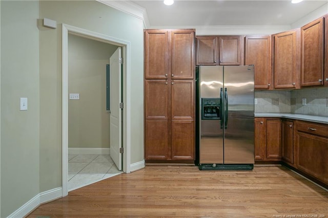 kitchen with stainless steel fridge, light wood-type flooring, and decorative backsplash