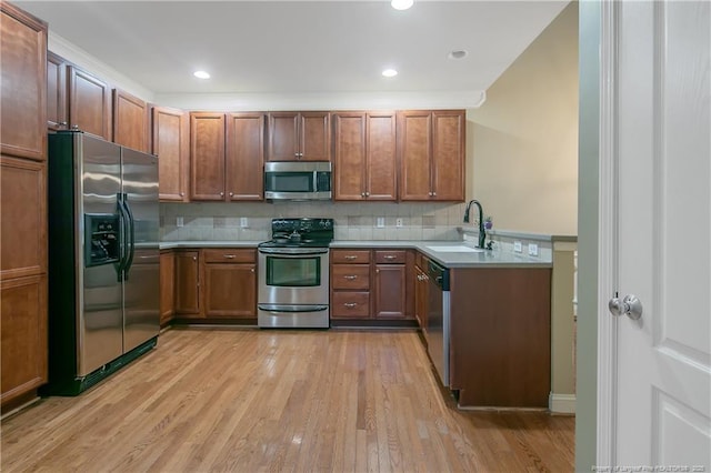 kitchen with decorative backsplash, appliances with stainless steel finishes, sink, and light hardwood / wood-style flooring