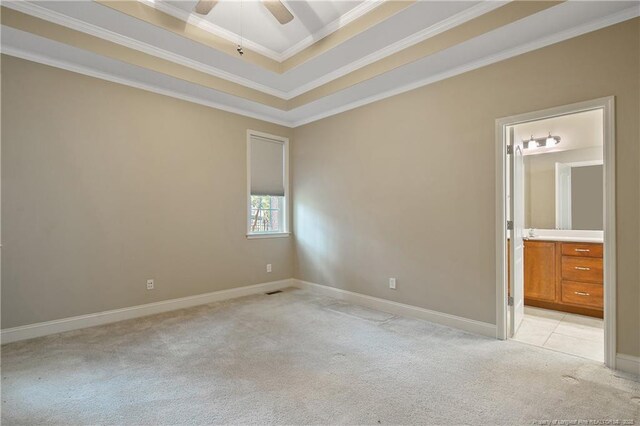 empty room featuring crown molding, ceiling fan, a tray ceiling, and light carpet