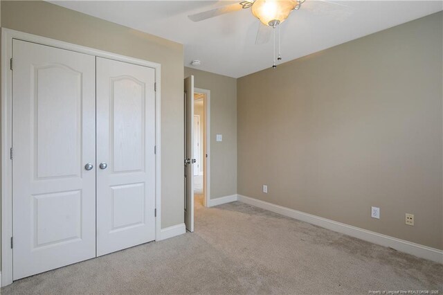 unfurnished bedroom featuring light carpet, ceiling fan, and a closet