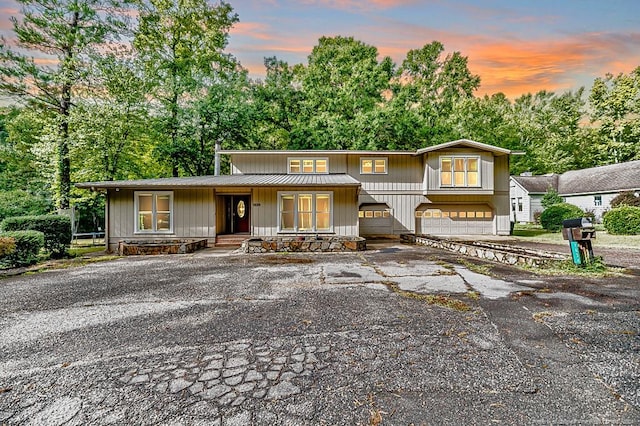 view of front of house with metal roof, driveway, covered porch, and a garage