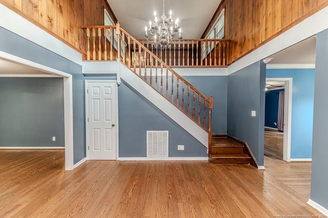 stairway featuring an inviting chandelier, ornamental molding, hardwood / wood-style flooring, and a high ceiling