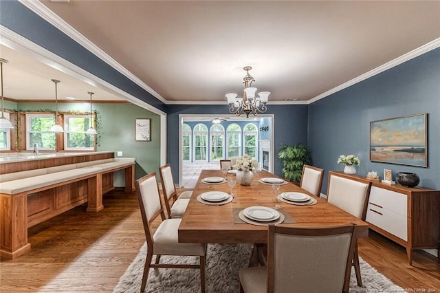 dining room with sink, crown molding, hardwood / wood-style floors, and a chandelier