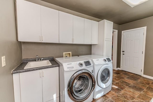 clothes washing area featuring independent washer and dryer, sink, and cabinets