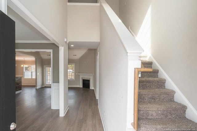 5737 Pooh Ave, Stedman, NC 28391 - staircase featuring wood finished floors, a fireplace, a towering ceiling, baseboards, and a chandelier