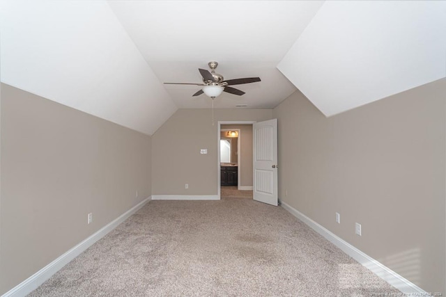 additional living space with ceiling fan, light colored carpet, and vaulted ceiling