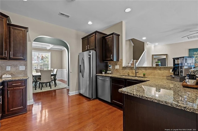 kitchen featuring light stone counters, decorative backsplash, dark wood-type flooring, and stainless steel appliances