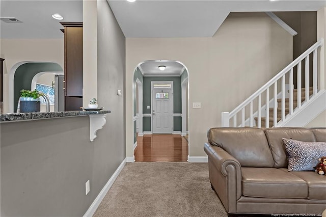 foyer with ornamental molding and light carpet