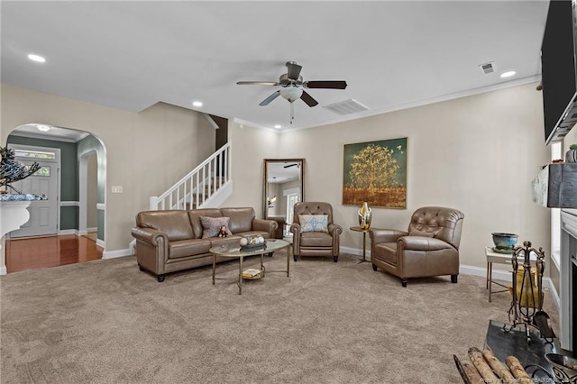 carpeted living room featuring ornamental molding and ceiling fan