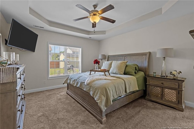 bedroom with light carpet, ceiling fan, and a tray ceiling