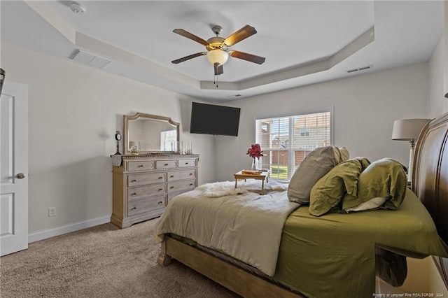 carpeted bedroom with ceiling fan and a raised ceiling