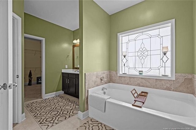 bathroom featuring tile patterned flooring, plenty of natural light, a tub to relax in, and vanity