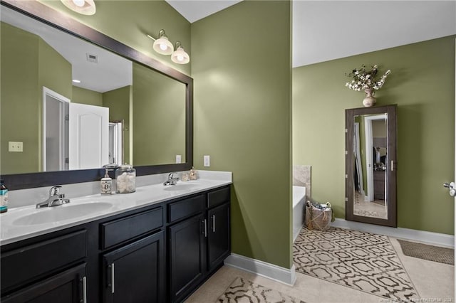 bathroom with tile patterned floors, a tub, and vanity