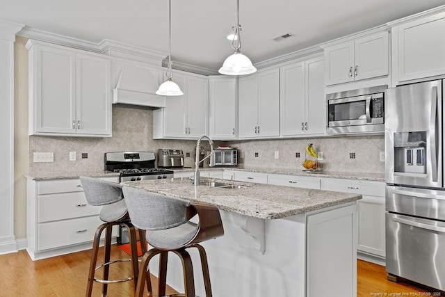 kitchen featuring a center island with sink, appliances with stainless steel finishes, and white cabinetry