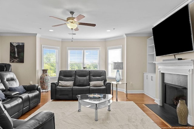 living room with hardwood / wood-style flooring, ceiling fan, and crown molding