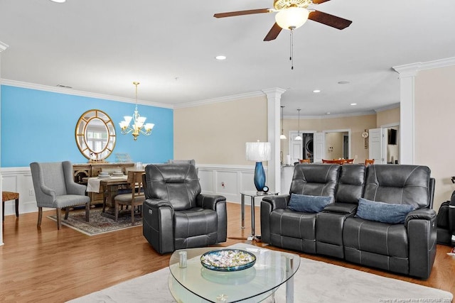 living room featuring ornamental molding, light hardwood / wood-style floors, ceiling fan with notable chandelier, and ornate columns