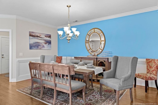 dining space with an inviting chandelier, crown molding, and hardwood / wood-style floors