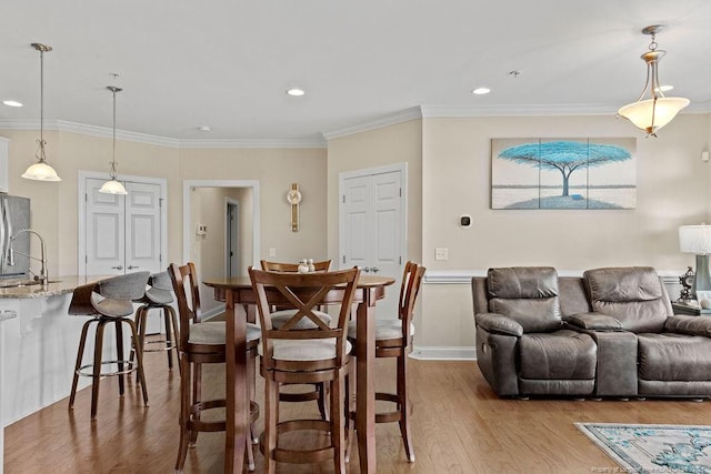 dining space featuring ornamental molding, light hardwood / wood-style flooring, and sink