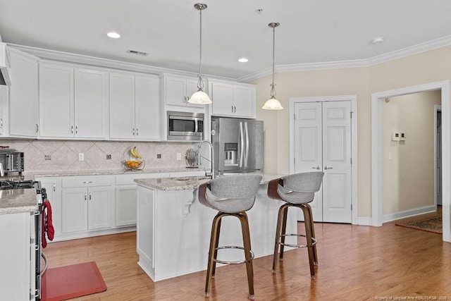 kitchen with stainless steel appliances, sink, white cabinetry, an island with sink, and pendant lighting