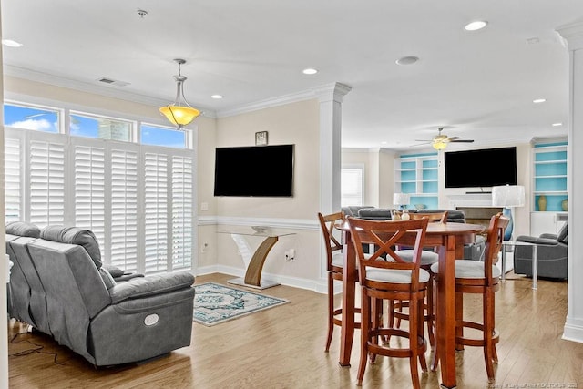 dining area featuring built in shelves, ceiling fan, light hardwood / wood-style floors, and crown molding