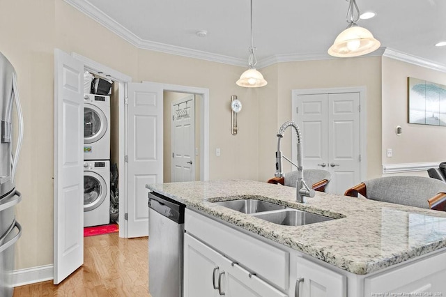 kitchen featuring white cabinets, a center island with sink, stacked washer / dryer, and stainless steel appliances