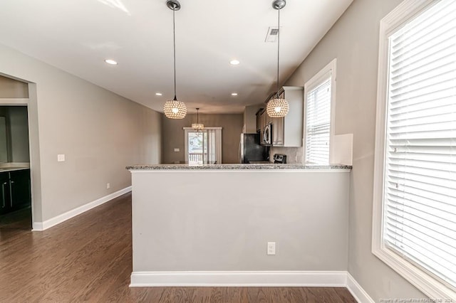 kitchen with light stone counters, kitchen peninsula, decorative light fixtures, appliances with stainless steel finishes, and dark hardwood / wood-style floors