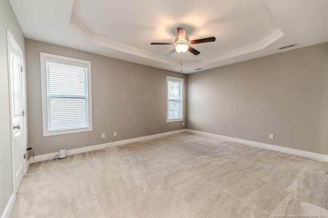 carpeted empty room with crown molding, ceiling fan, and a raised ceiling