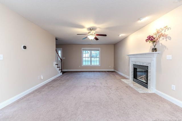 unfurnished living room with ceiling fan, light colored carpet, and a fireplace