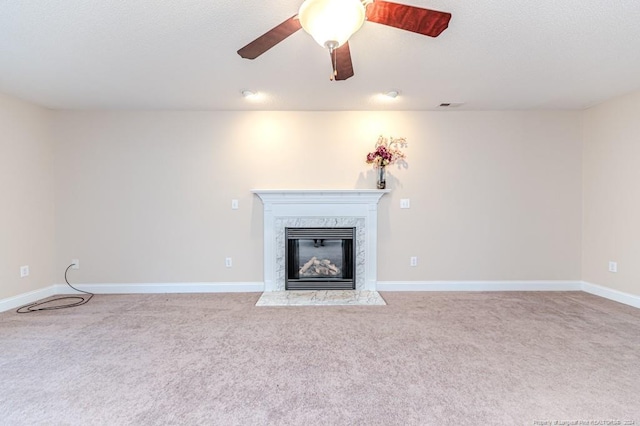 unfurnished living room featuring a premium fireplace, ceiling fan, and light colored carpet