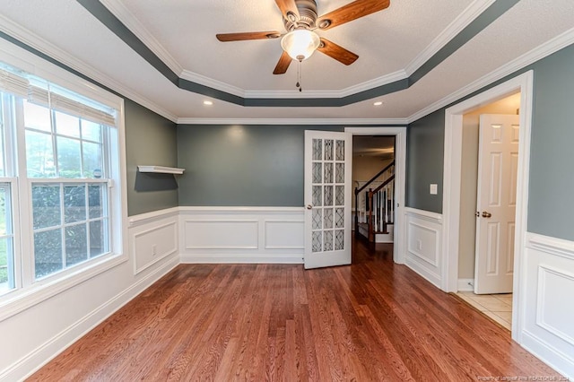 3375 Carolina Way, Sanford, NC 27332 - empty room featuring a tray ceiling, wood finished floors, stairway, wainscoting, and ornamental molding