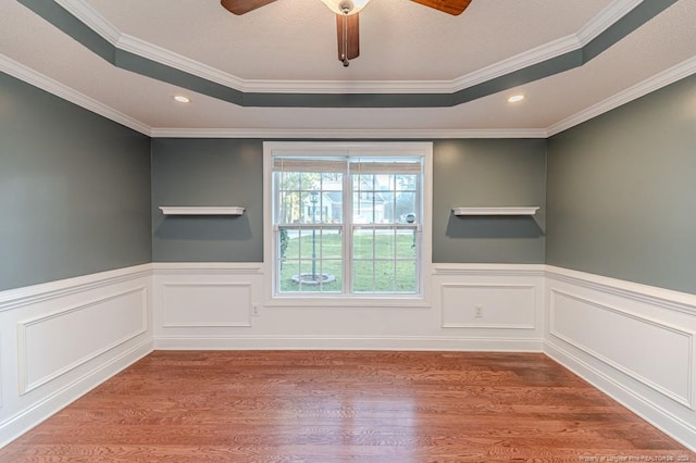 3375 Carolina Way, Sanford, NC 27332 - spare room featuring a tray ceiling, wood finished floors, a ceiling fan, ornamental molding, and a wainscoted wall