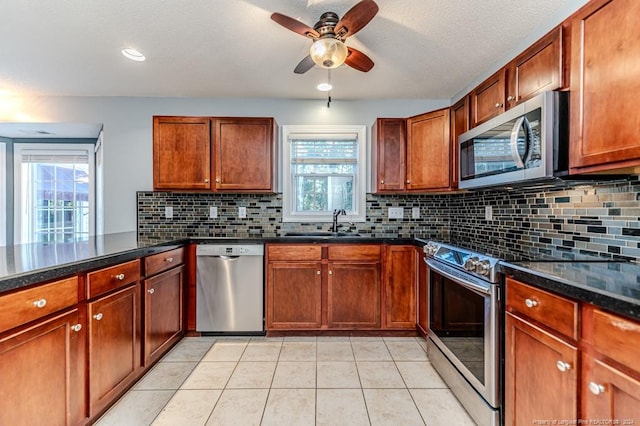 kitchen with stainless steel appliances, ceiling fan, light tile patterned floors, and a healthy amount of sunlight