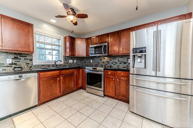 3375 Carolina Way, Sanford, NC 27332 - kitchen featuring appliances with stainless steel finishes, a sink, dark countertops, a ceiling fan, and decorative backsplash