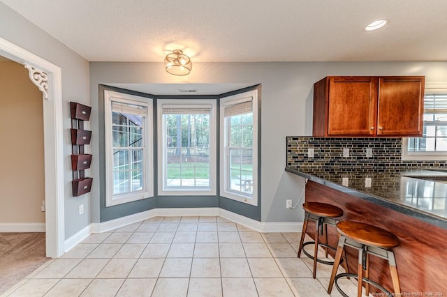 3375 Carolina Way, Sanford, NC 27332 - kitchen featuring brown cabinets, backsplash, baseboards, light tile patterned flooring, and a kitchen bar