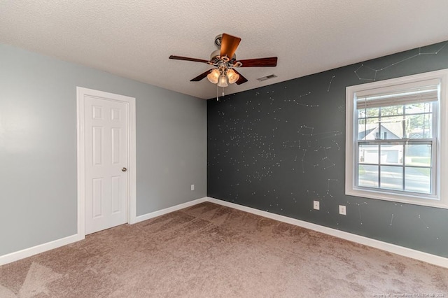 carpeted empty room featuring ceiling fan and a textured ceiling