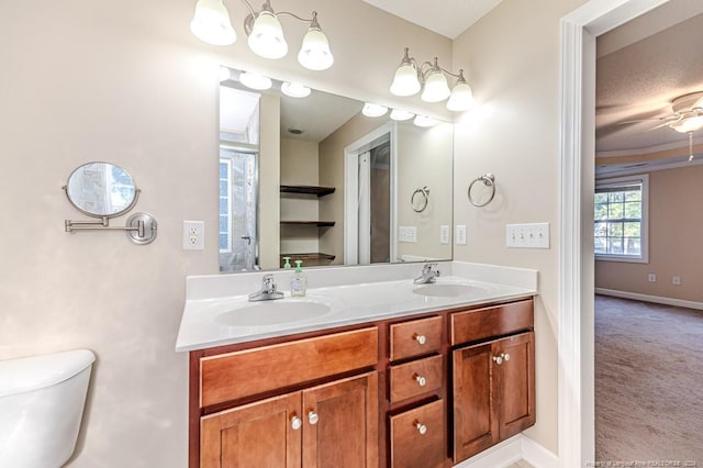 bathroom with ceiling fan, toilet, crown molding, vanity, and a textured ceiling