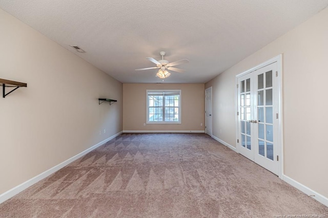 carpeted empty room with ceiling fan, a textured ceiling, and french doors