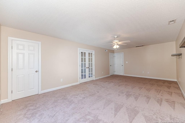 empty room with a textured ceiling, ceiling fan, french doors, and light colored carpet