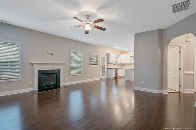 unfurnished living room featuring ceiling fan and dark wood-type flooring