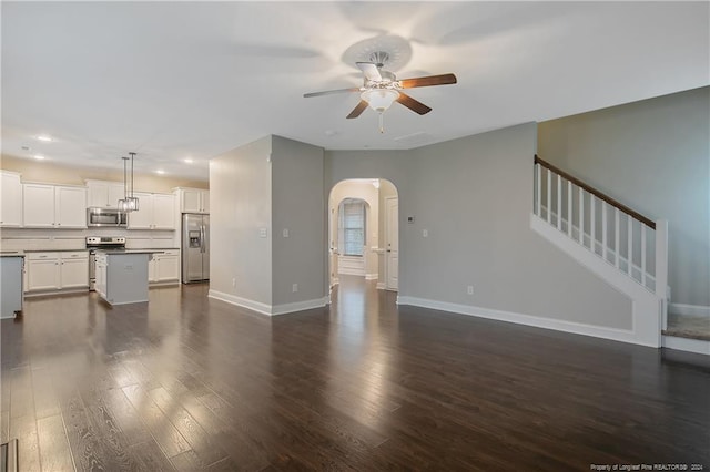 unfurnished living room featuring dark wood-type flooring and ceiling fan