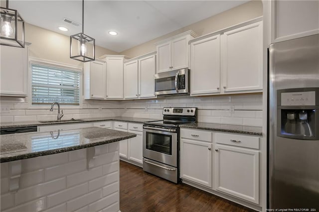 kitchen featuring pendant lighting, stainless steel appliances, dark stone counters, and white cabinetry